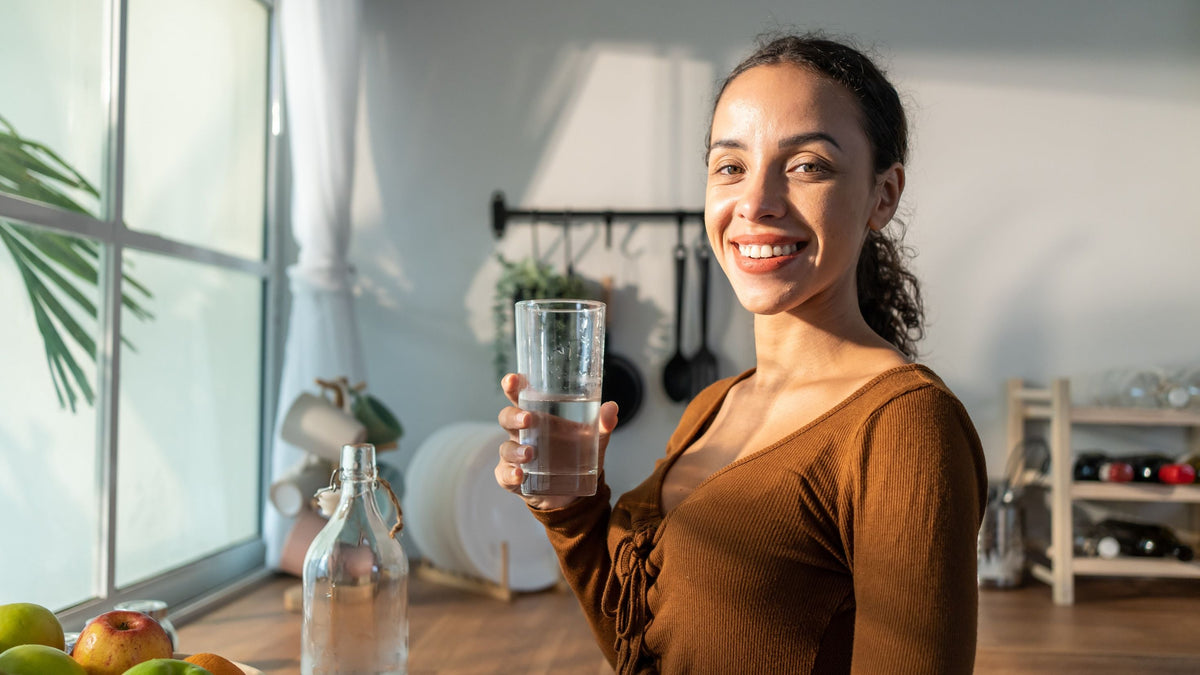 Frau in der Küche mit einem Glas Wasser in der Hand