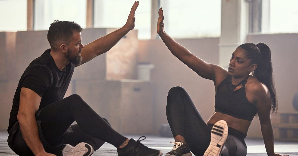 Coach und Athletin geben sich nach einer intensiven Trainingseinheit im Functional-Fitness-Studio ein High Five.