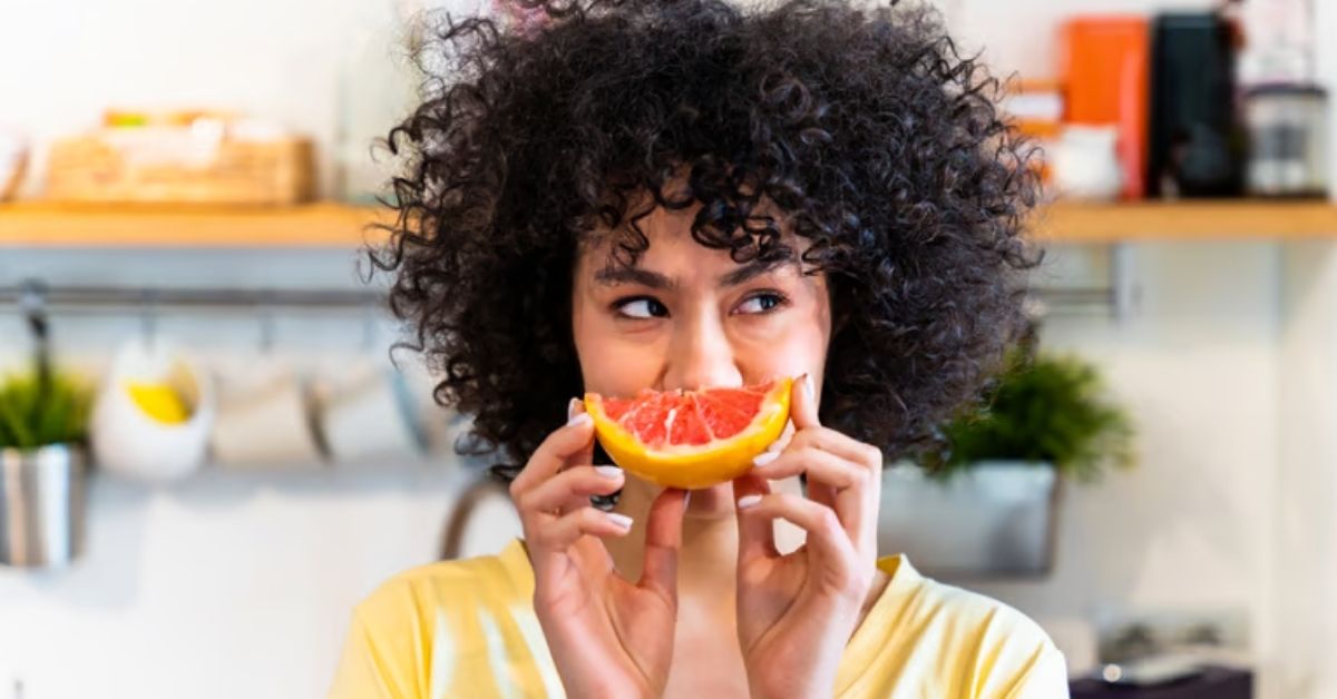 Frau isst eine Grapefruit als natürliche Quelle für Bitterstoffe.