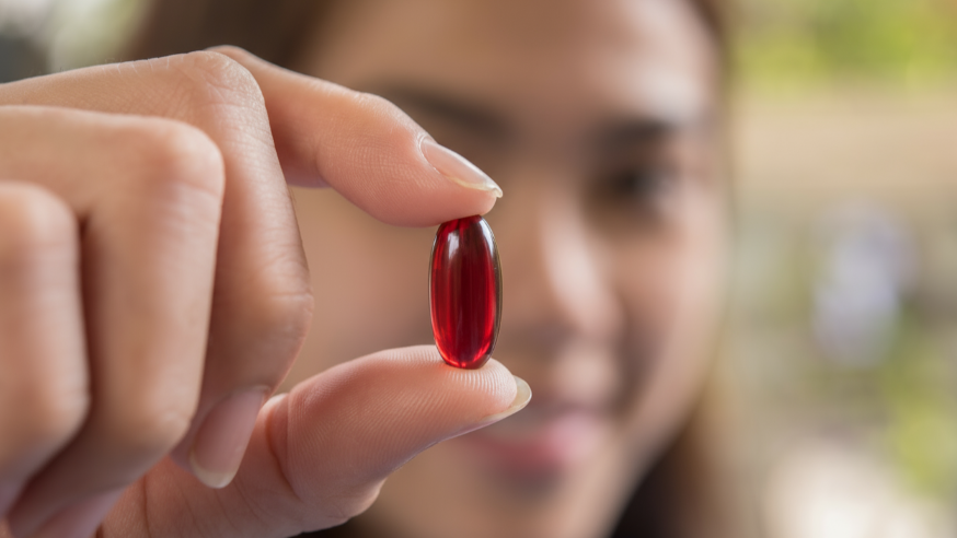 Kurkuma einnehmen: Frau hält eine Kurkuma-Kapsel in der Hand