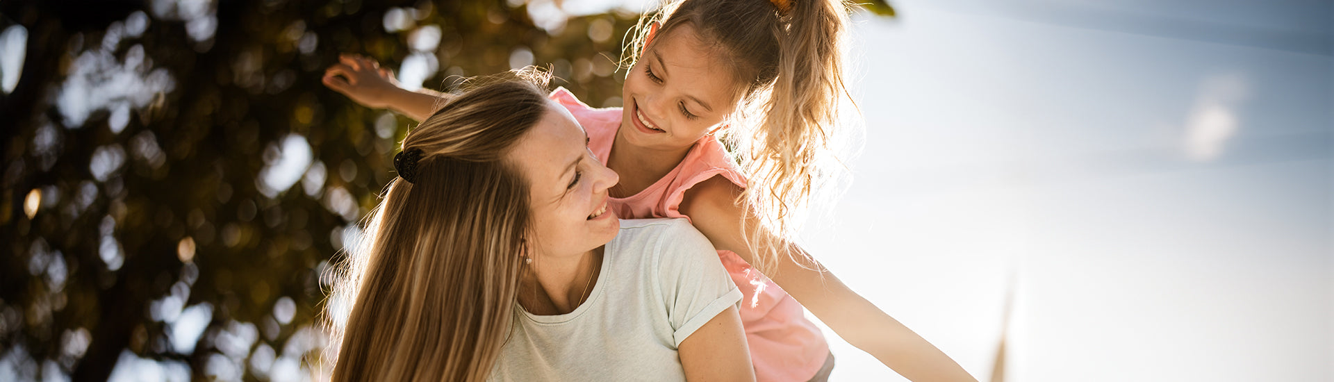 Mutter nimmt Tochter auf den Rücken und das Kind breitet die Arme aus