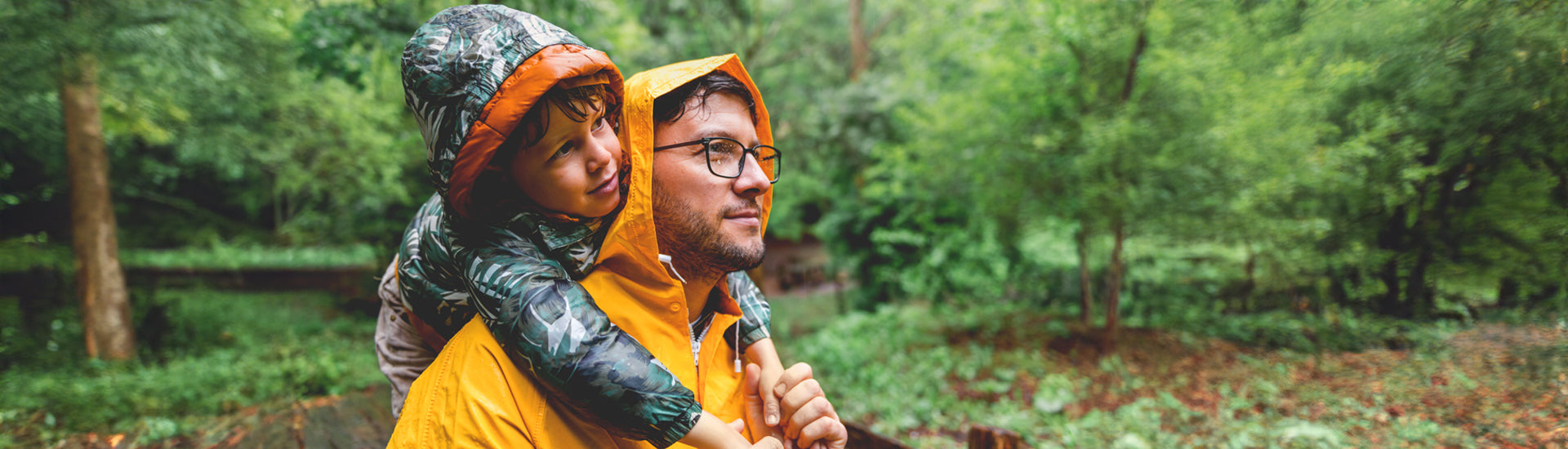 Vater nimmt Sohn auf die Schultern und sind im Wald