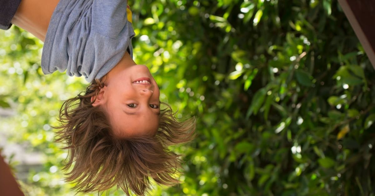 Kind hängt kopfüber an einem Spielgerät – impulsives und riskantes Verhalten kann bei ADHS-Symptomen bei Kindern auftreten