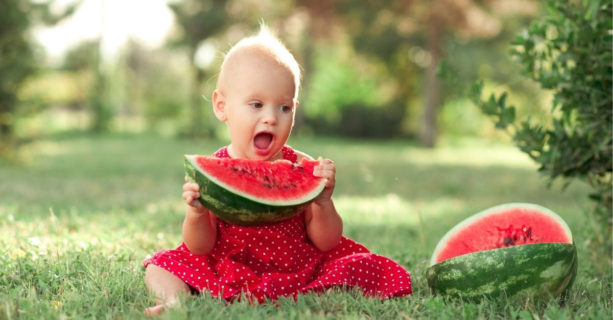Baby isst eine große Scheibe Wassermelone – Obst und weiches Fingerfood als Teil des Beikostplans