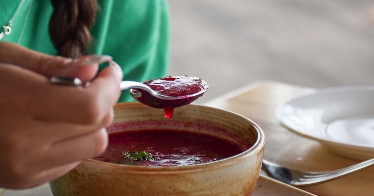 Person isst Rote-Bete-Suppe mit einem Löffel aus einer Keramikschale.