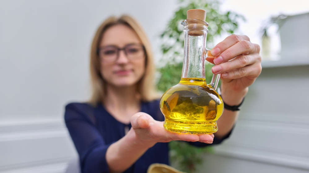 Frau hält eine Flasche mit goldenem Leinöl in der Hand – hochwertiges Leinöl für eine gesunde Ernährung.