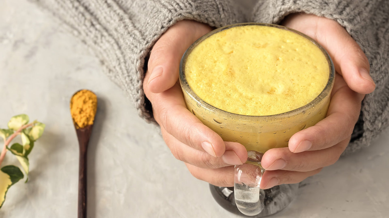 Frau hält Tasse mit Goldener Milch in der Hand