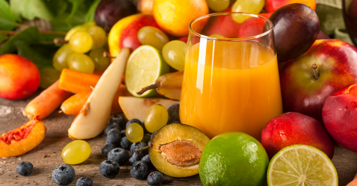 Frisches Obst mit Orangen, Äpfeln, Trauben, Beeren und Karotten sowie einem Glas Fruchtsaft als natürliche Vitaminquellen.