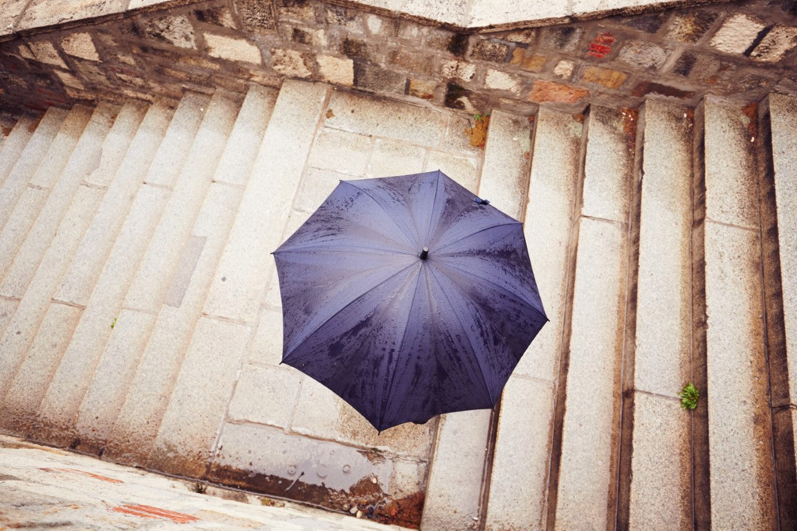Regenschirm von oben auf eine beigen Treppe