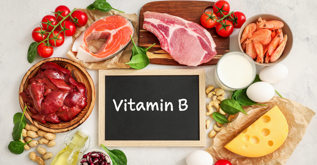 Vitamin-B-reiche Lebensmittel wie Lachs, Fleisch, Eier, Milchprodukte, Nüsse und Leber rund um eine Tafel mit der Aufschrift Vitamin B.