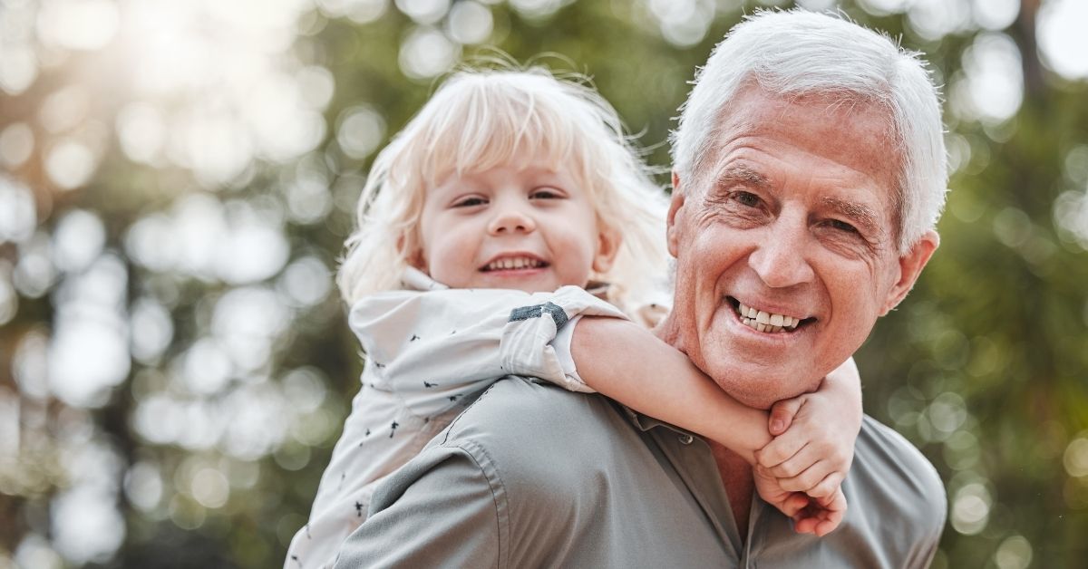 Vitamin-B12-Tagesbedarf in jeder Lebensphase – aktiver Senior mit Kind im Freien