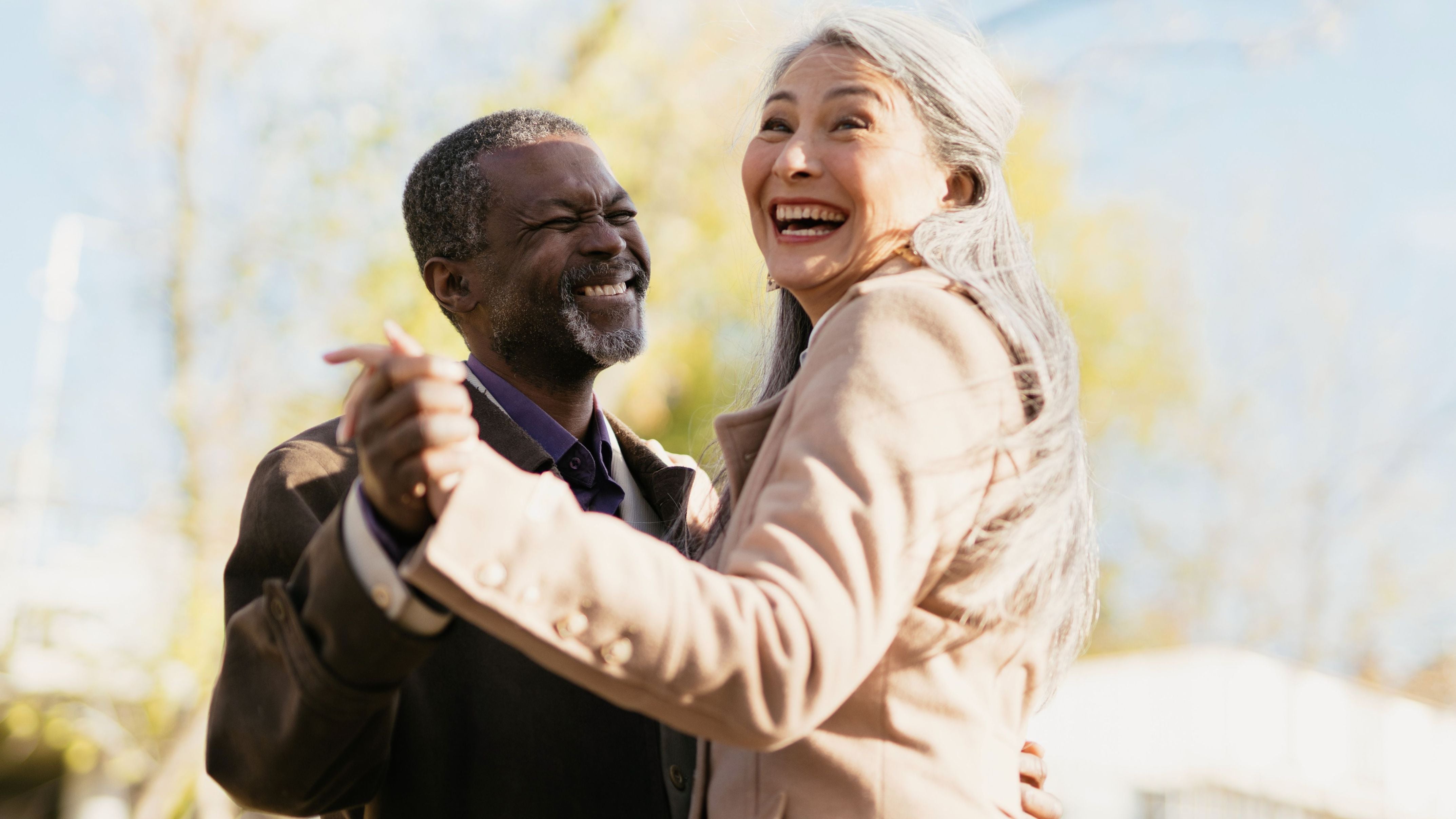 Longevity: Älteres Paar, das lachend im Freien tanzt – voller Lebensfreude und Energie.