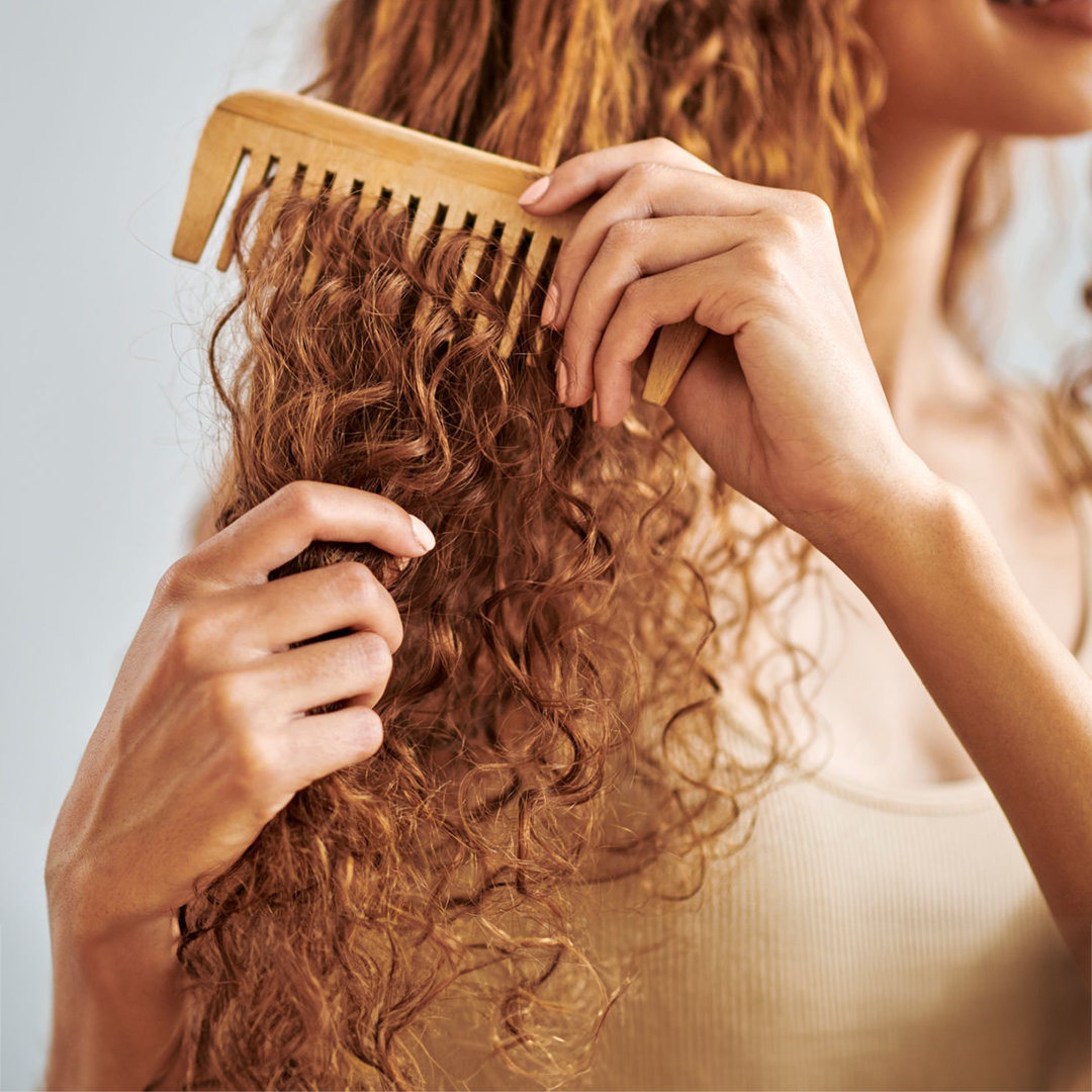 Frau mit Locken kämmt sich die Haare