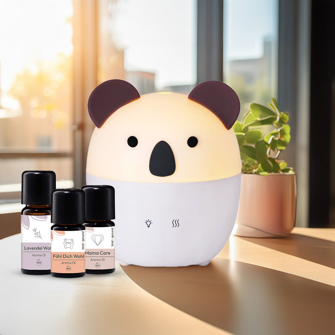 Drei Aroma Öle, ein Koala Diffuser und eine Pflanze stehen bei Sonnenlicht im Wohnzimmer.